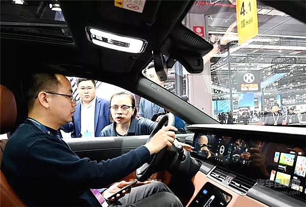 4月17日，参观者（左）在一部采用电动增程技术的理想ONE电动车驾驶舱内体验车载电子设备