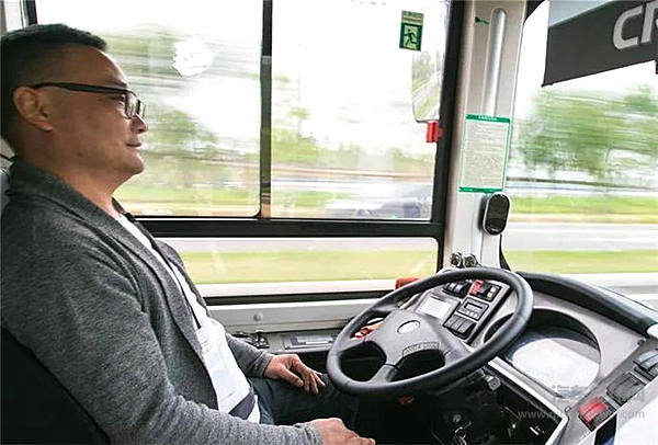 一辆无人驾驶公交车在国家智能网联汽车（长沙）测试区内行驶，驾驶座位的测试员关注路况和驾驶数据